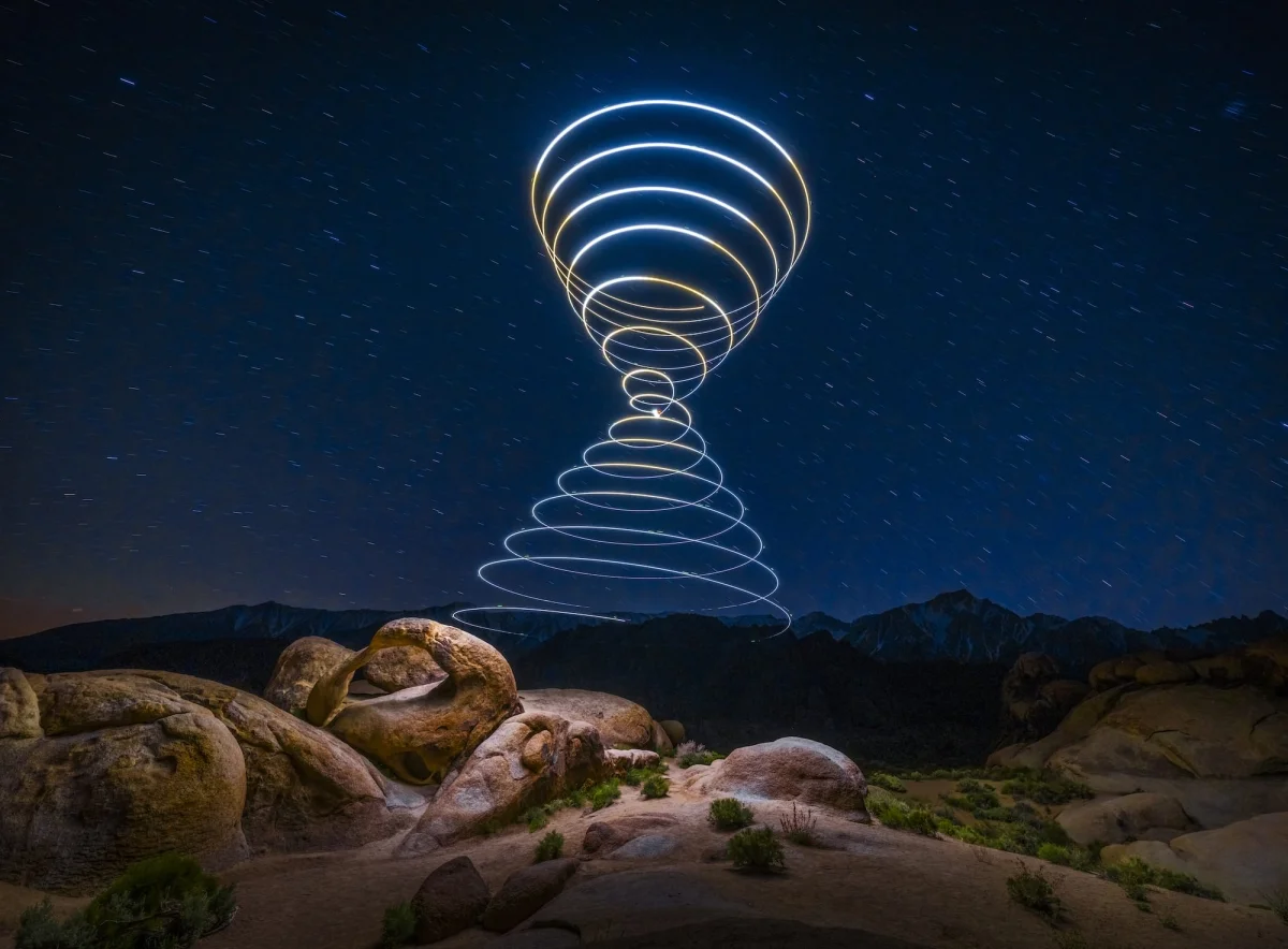 a "light painting" photograph with a double cone of swirling light, created using a drone, over a dramatically lit nighttime desert landscape