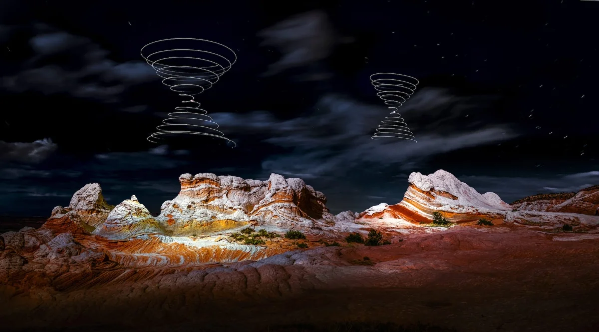 a "light painting" photograph with two double cones of swirling light, created using a drone, over a dramatically lit nighttime desert landscape